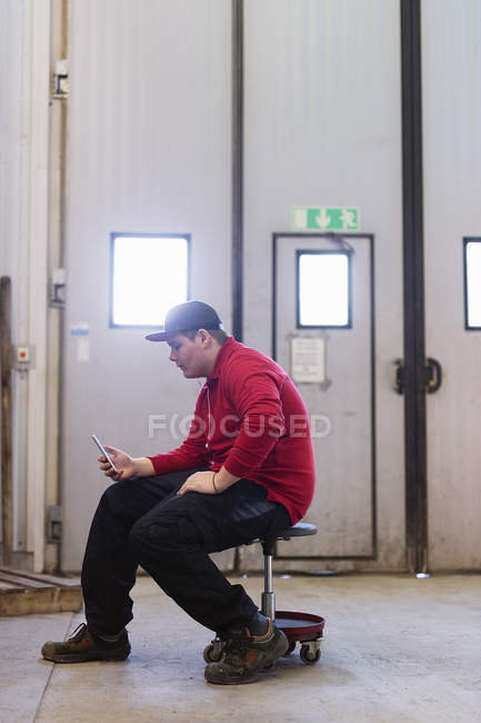 Мальчик-подросток сидит и использует смартфон — стоковое фото