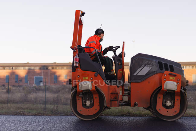 Side view of manual worker driving steamroller — Stock Photo