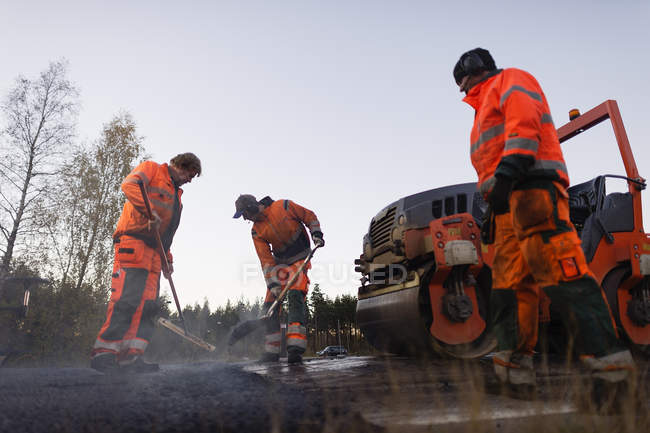 Три ручні працівники ремонтують дорогу — стокове фото