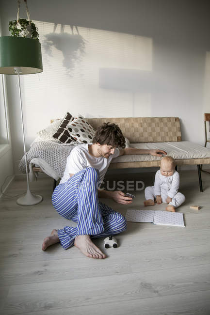 Father and baby son sitting on floor in living room — Stock Photo