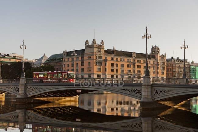 Bridge with moving bus and buildings in Stockholm old town reflecting in water — Stock Photo