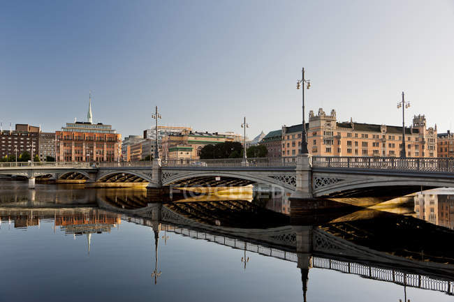 Brücke und Gebäude in Stockholms Altstadt spiegeln sich im Wasser — Stockfoto