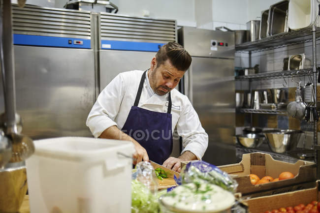 Шеф-повар режет овощи, сосредоточиться на фоне — стоковое фото
