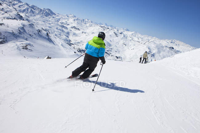 Вид сзади на катание на лыжах на склоне горы — стоковое фото