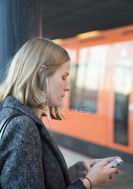 Jovem mulher usando smartphone na estação de metrô — Fotografia de Stock