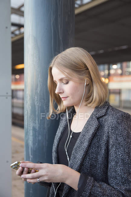 Jovem mulher ouvindo música na estação de metrô — Fotografia de Stock