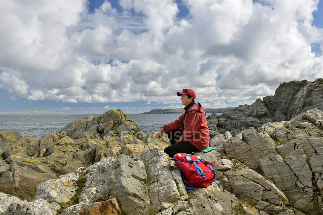 Seitenansicht einer Seniorin, die auf einem Felsen sitzt — Stockfoto