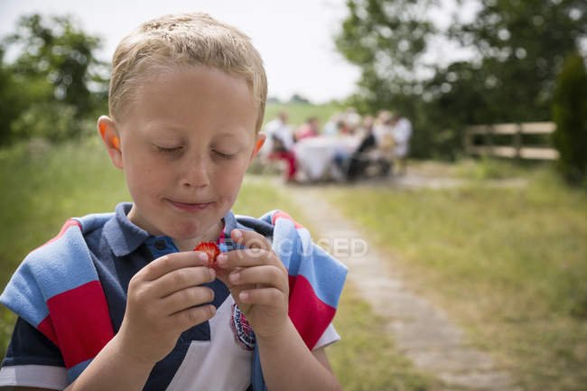 Junge isst Erdbeere, Fokus auf Vordergrund — Stockfoto