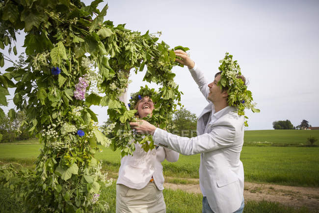 Mujer y hombre organizando guirnaldas florales para celebraciones de verano - foto de stock