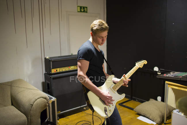 Молодий чоловік грає на гітарі, зосереджується на передньому плані — стокове фото