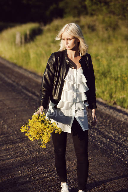 Молодая женщина с кучей полевых цветов — стоковое фото