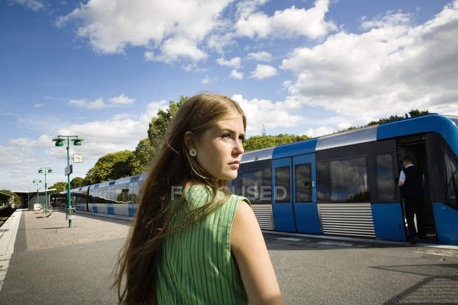 Teenage girl standing on railroad station platform — Stock Photo