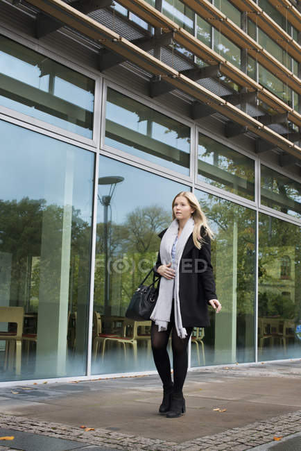 Jeune femme blonde marchant par l'université — Photo de stock