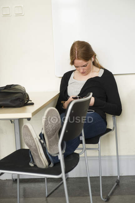 Молодая женщина, использующая мобильный телефон в классе — стоковое фото