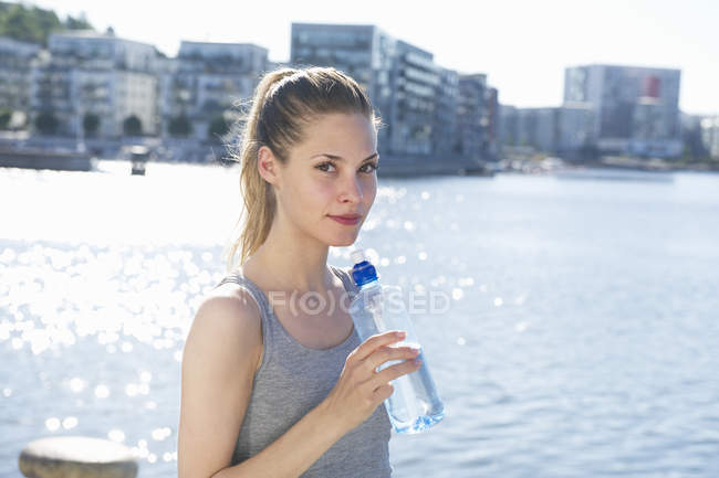 Mulher de pé com garrafa de água nas mãos — Fotografia de Stock