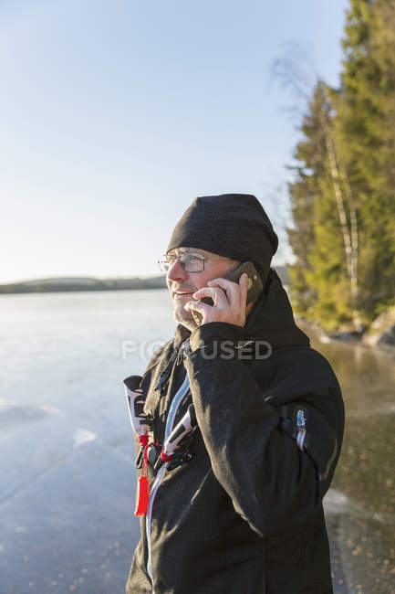 Зріла жінка використовує мобільний телефон на замерзлому озері — стокове фото