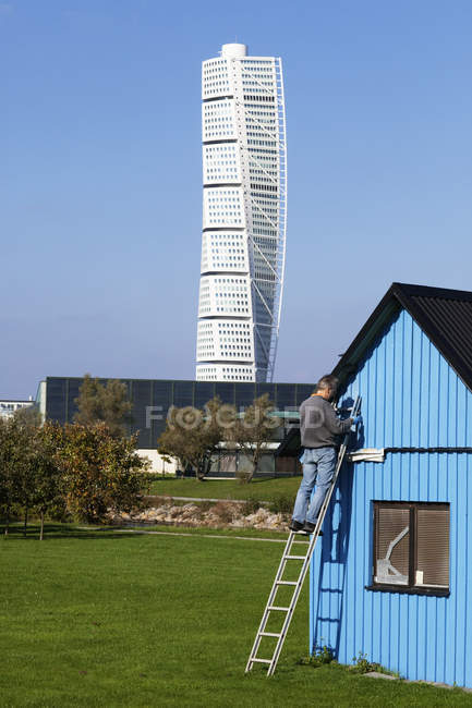 Man on ladder by hut and Turning Torso tower in background — Stock Photo