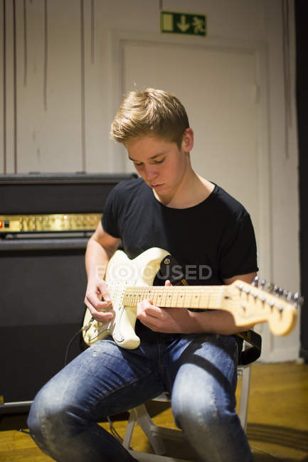 Jovem tocando guitarra na sala de estar — Fotografia de Stock