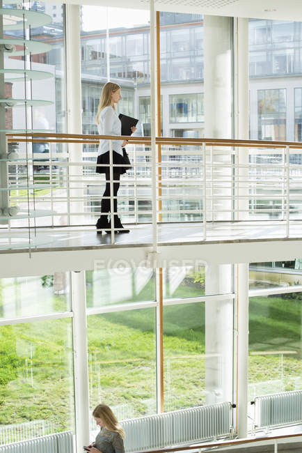 Young woman holding folder on second floor of university building — Stock Photo