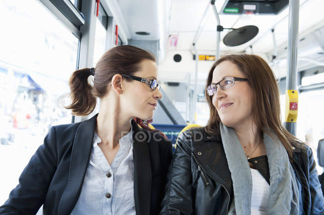 Dos mujeres viajando en autobús y mirándose - foto de stock