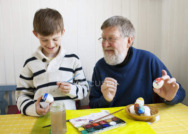 Дедушка с внуком украшает пасхальные яйца — стоковое фото