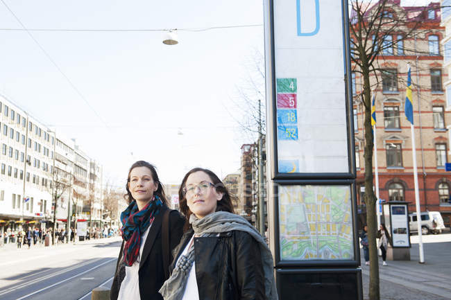 Дві жінки, що стоять на вулиці і дивляться в сторону — стокове фото