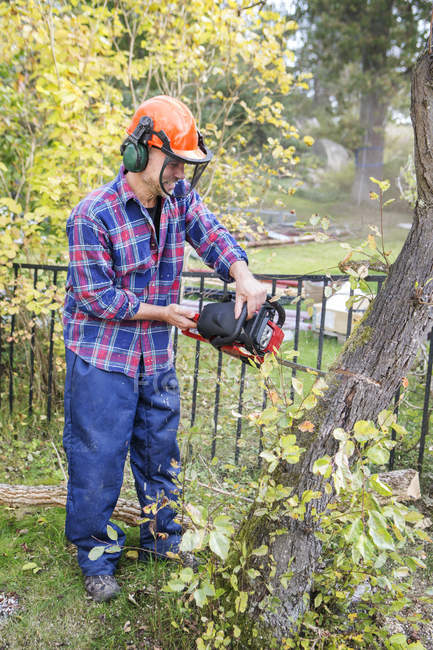 Man cutting trees, focus on foreground — Stock Photo