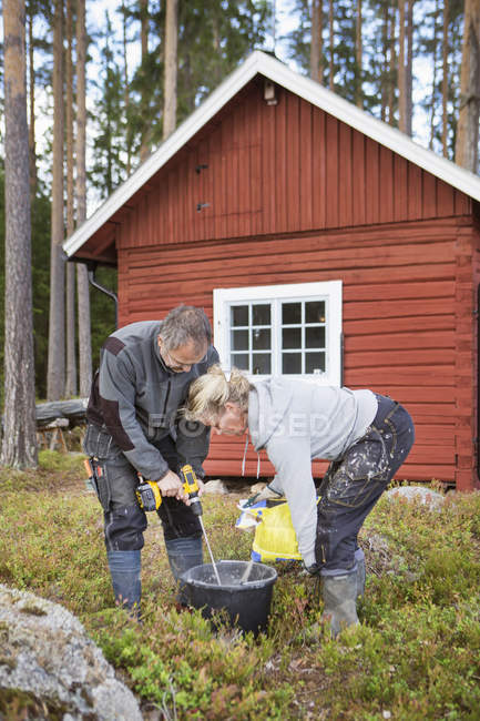 Мужчина и женщина смешивают бетон, фокусируйтесь на переднем плане — стоковое фото