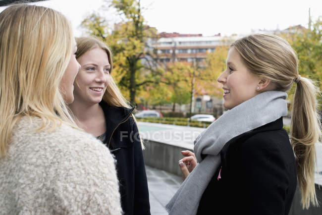 Jóvenes estudiantes universitarios alegres hablando en el campus - foto de stock