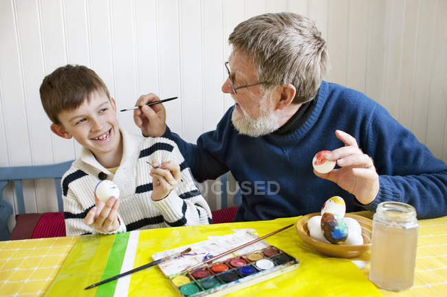 Grandfather with grandson decorating Easter eggs — Stock Photo