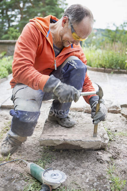 Hombre rompiendo piedra con martillo y cincel - foto de stock