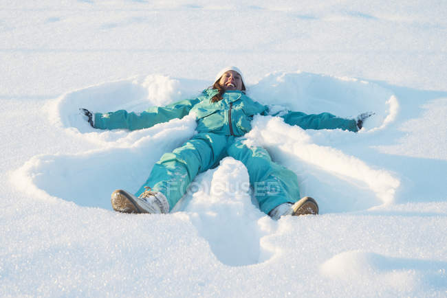 Frau macht Schnee-Engel auf dem Rücken liegend — Stockfoto