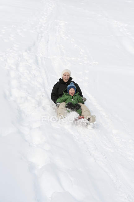 Mãe deslizando para baixo declive com a filha em Vorarlberg, Áustria — Fotografia de Stock