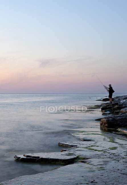 Homem pesca ao pôr do sol, foco seletivo — Fotografia de Stock