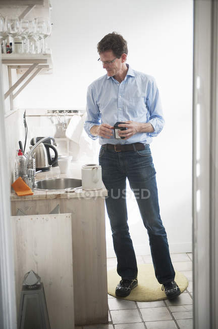 Чоловік стоїть біля раковини на домашній кухні — стокове фото
