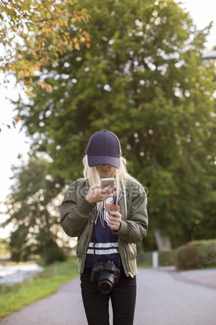 Girl photographing leaf with cell phone — Stock Photo