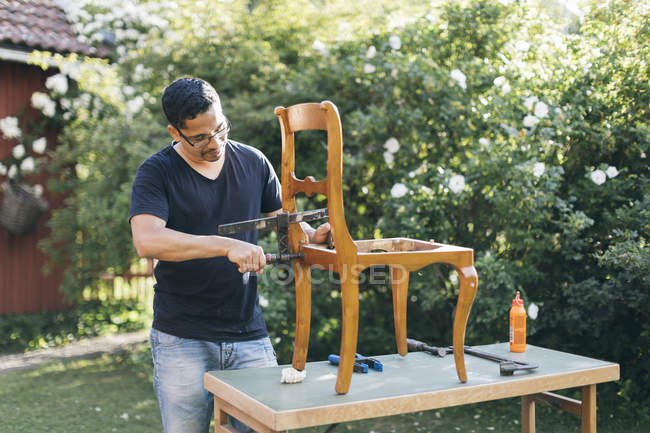 Mitte erwachsener Mann repariert Stuhl im Freien in kvarnstugan, Schweden — Stockfoto