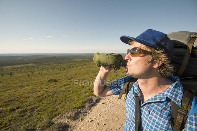 Hombre bebiendo de una botella en el Parque Nacional Pallas-Yllastunturi en Laponia, Finlandia - foto de stock