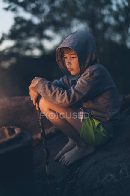 Niño sentado junto a la fogata, enfoque selectivo - foto de stock