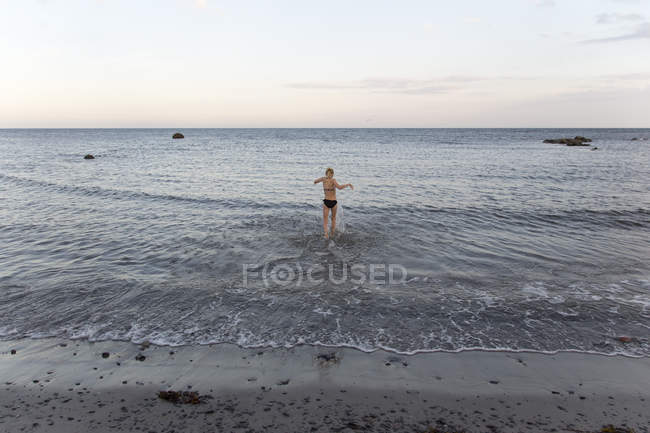 Rear view of girl in bikini wadding in sea in Ornahusen, Sweden — Stock Photo