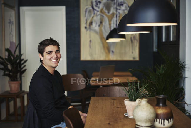 Молодий чоловік сидить у кафе, зосередьтеся на передньому плані — стокове фото