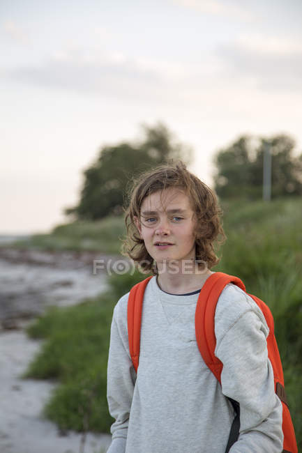 Ragazzo adolescente che indossa lo zaino sulla spiaggia, concentrarsi sul primo piano — Foto stock