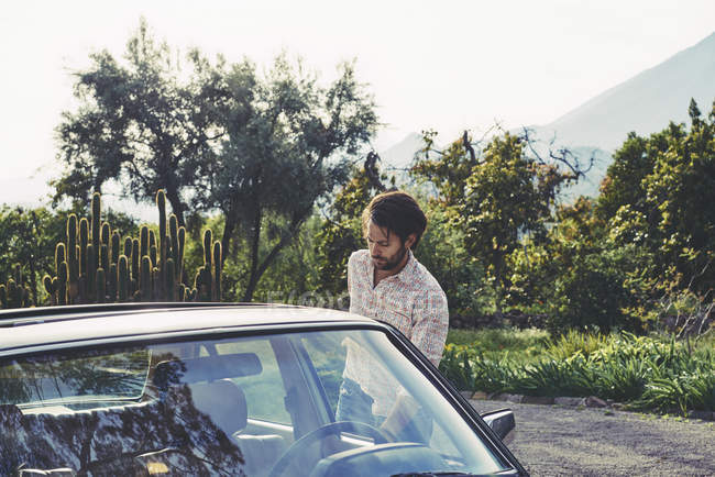 Mann im mittleren Erwachsenenalter steht mit Auto gegen Bäume — Stockfoto