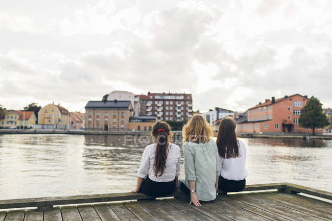 Три молодые женщины сидят на пирсе в Карлскруне, Швеция — стоковое фото