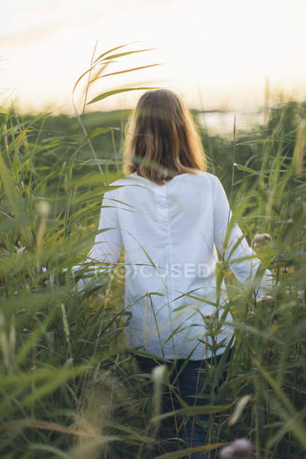 Young woman walking through field of grass in Karlskrona, Sweden — Stock Photo