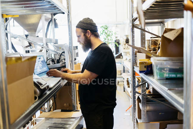 Coffee roaster using laptop, focus on foreground — Stock Photo
