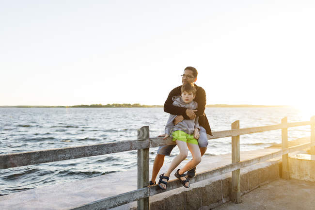 Padre e figlio seduti sul molo al tramonto a Blekinge, Svezia — Foto stock