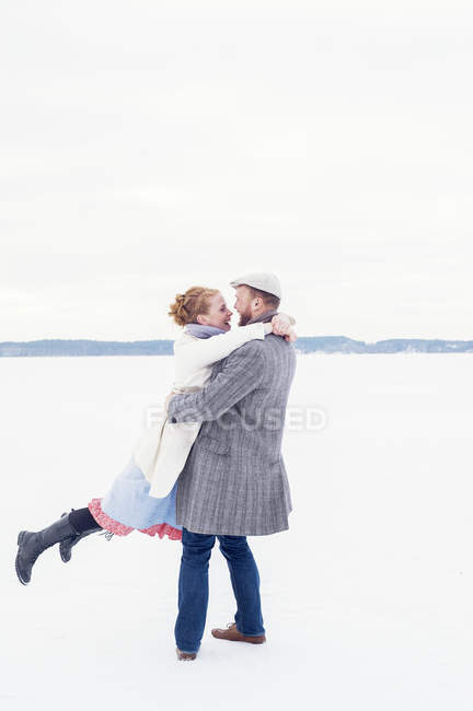 Vista laterale della giovane coppia che gioca nella neve, messa a fuoco selettiva — Foto stock
