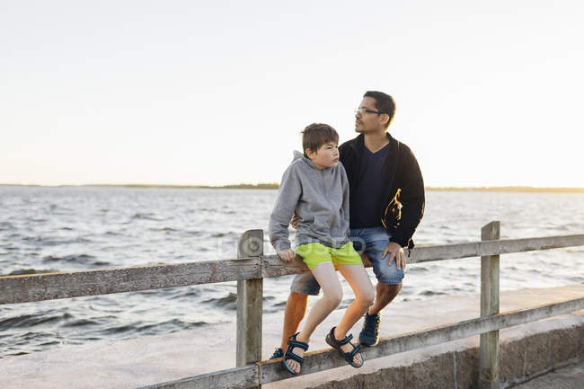 Батько і син сидять на пірсі на заході сонця в Блекінге, Швеція — стокове фото