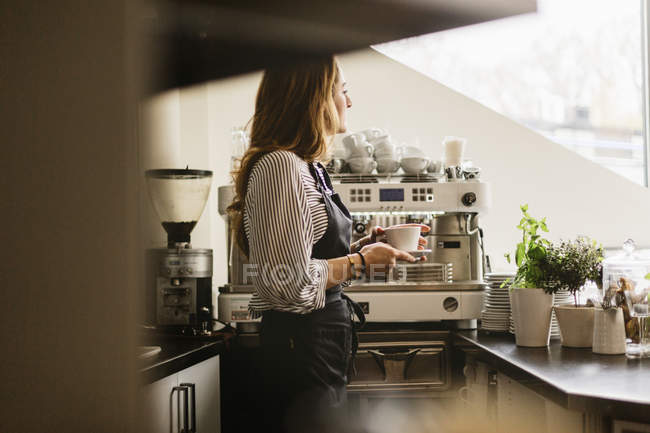 Barista segurando xícara de café na cozinha do café, foco seletivo — Fotografia de Stock